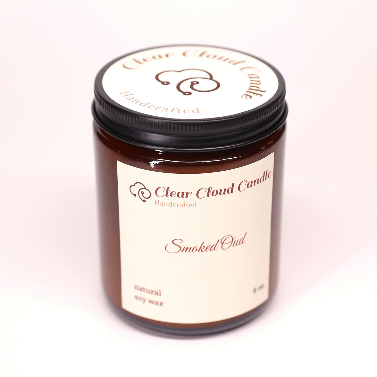 amber glass candle jar. light cream label. round cream label on jar top. scent name: smoked oud