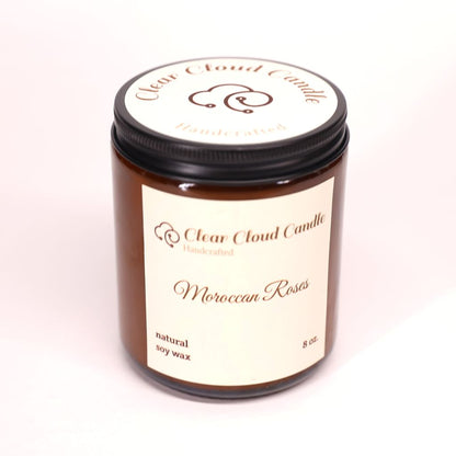 Amber color Candle jar labeled 'Moroccan Roses' by 'Clear Cloud Candle' on a white background