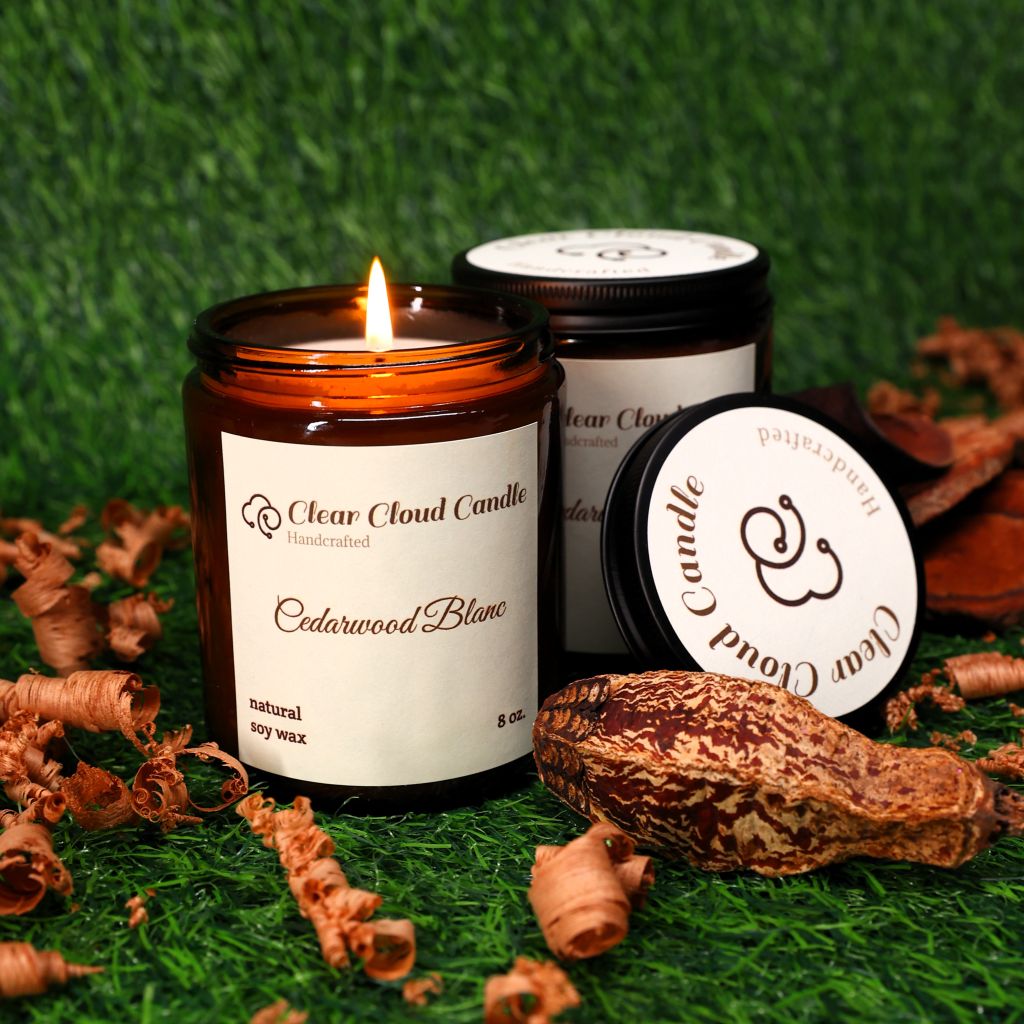 Cedarwood scented Candle with 'Clear Cloud Candle' Co. label on a green grass background with wood shavings