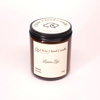 Clear Cloud Candle Amber jar with 'Lemon Zest' scented candle on a white background